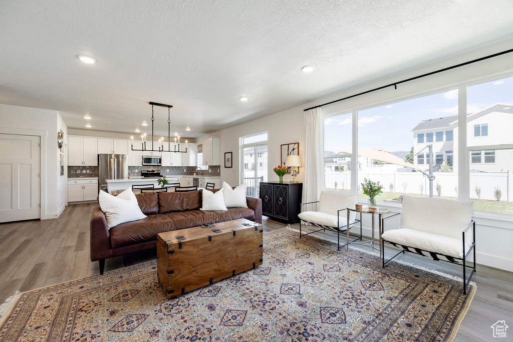 Living room with light wood-style flooring, a chandelier, recessed lighting, and a textured ceiling