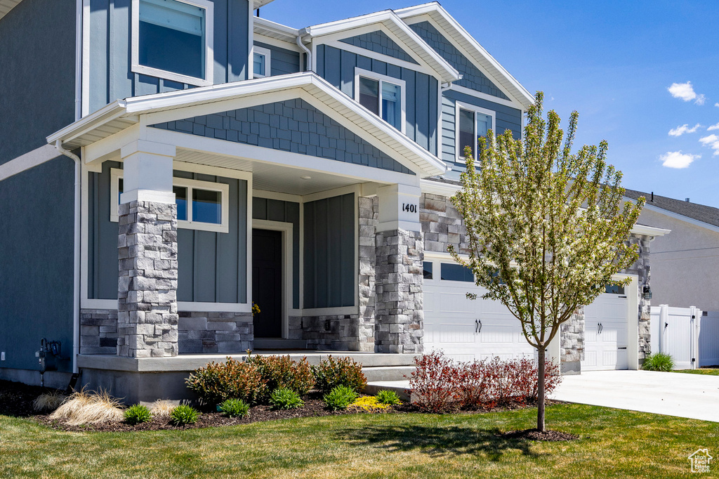 View of front of property featuring stone siding, concrete driveway, and board and batten siding