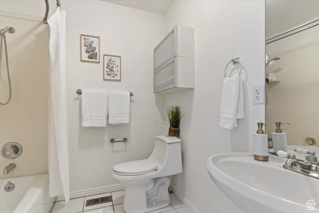 Bathroom featuring a sink, baseboards, toilet, shower / bath combo, and tile patterned flooring
