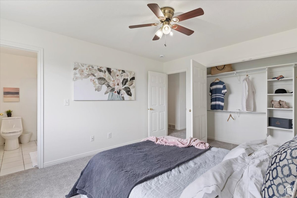 Bedroom featuring carpet, baseboards, ensuite bath, a ceiling fan, and a closet