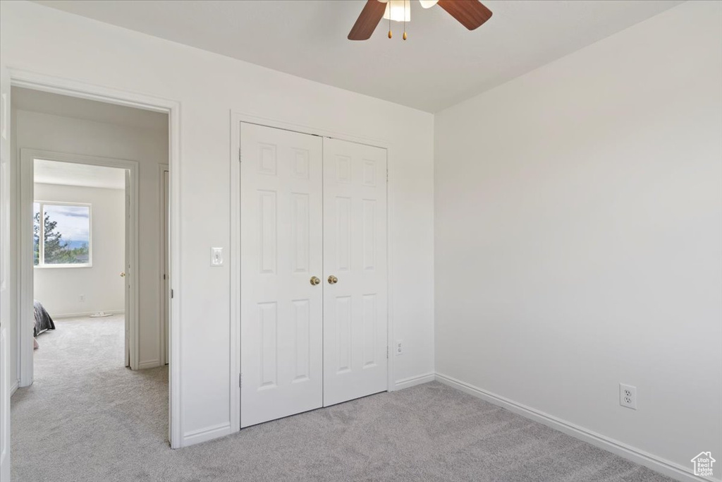 Unfurnished bedroom with carpet flooring, baseboards, a closet, and a ceiling fan