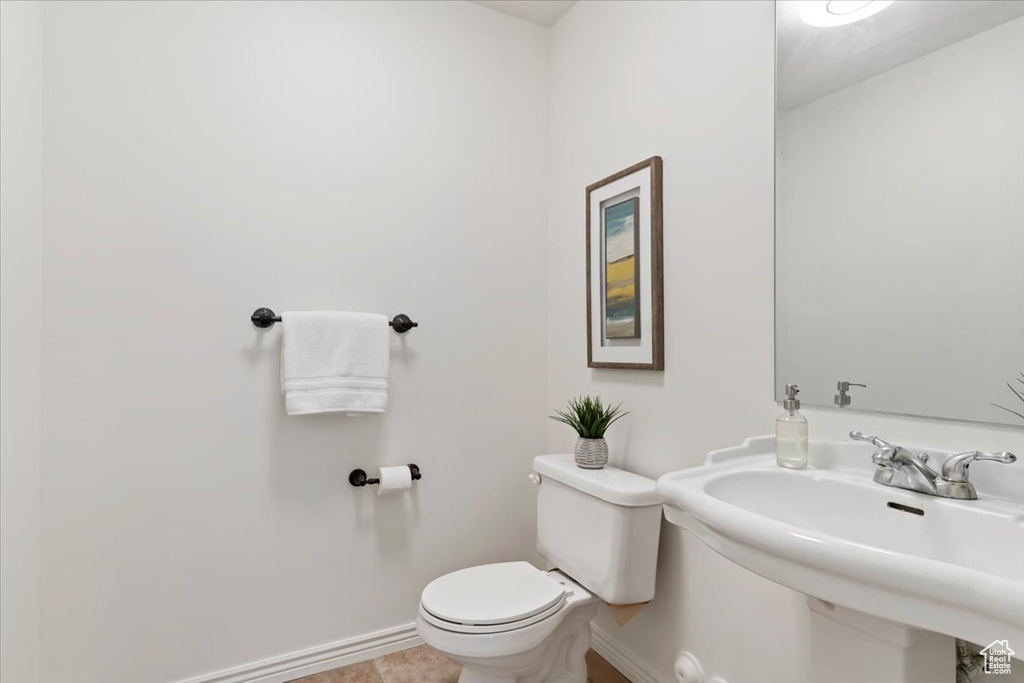 Half bathroom featuring baseboards, toilet, and a sink