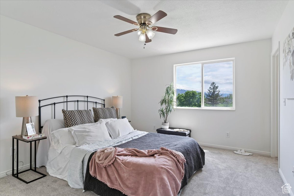 Bedroom with light colored carpet, baseboards, and a ceiling fan