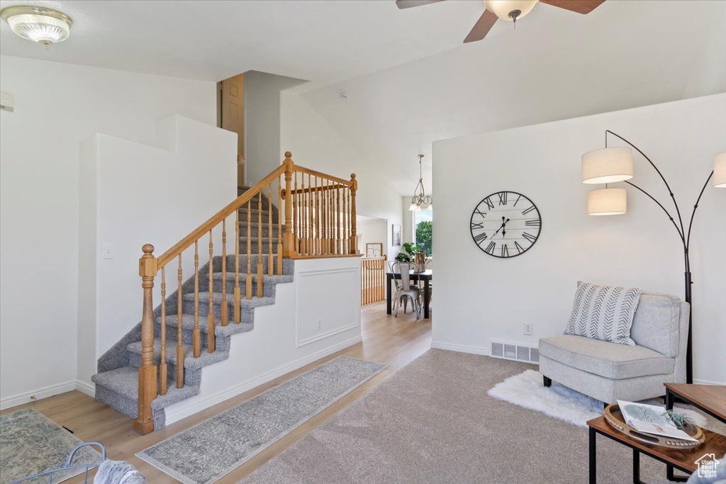 Stairs with a ceiling fan, high vaulted ceiling, baseboards, and wood finished floors