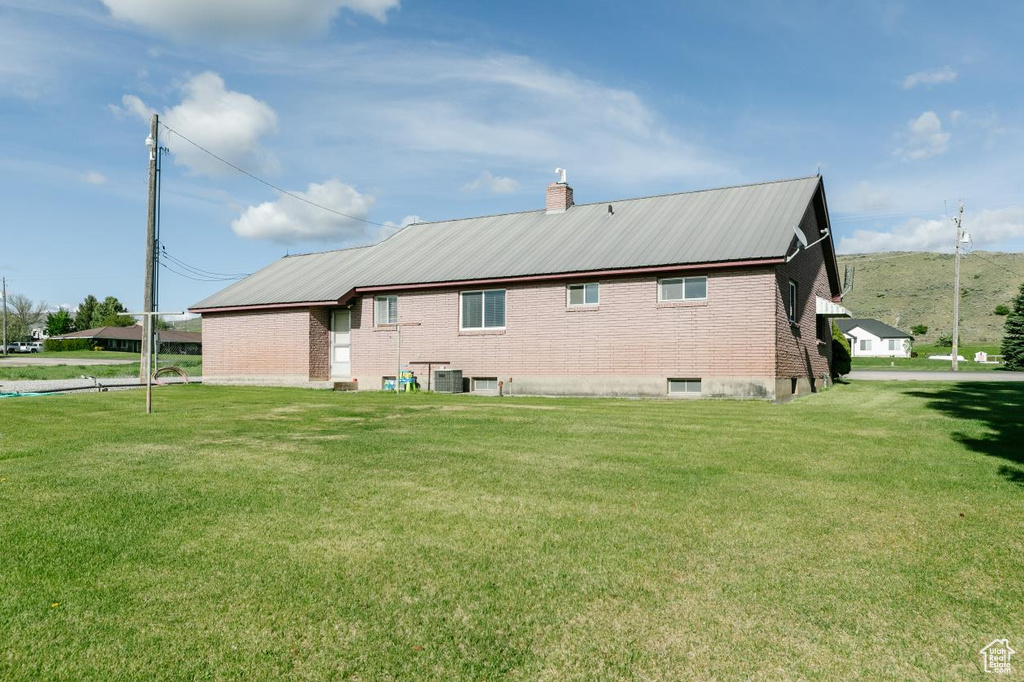 Back of property with a yard, brick siding, and a chimney