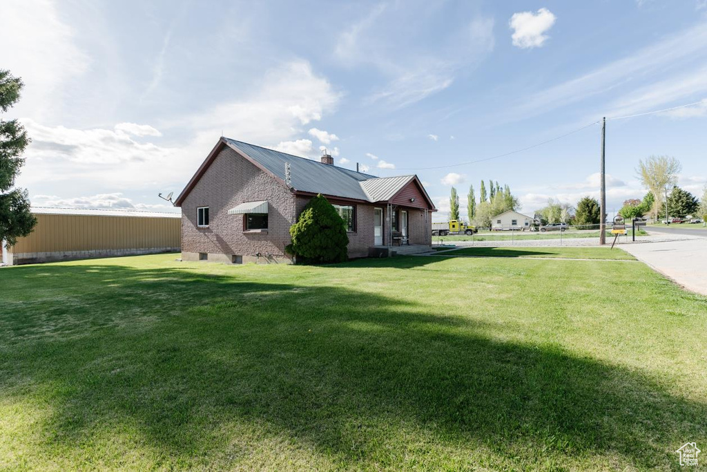 View of property exterior featuring metal roof, a chimney, and a lawn