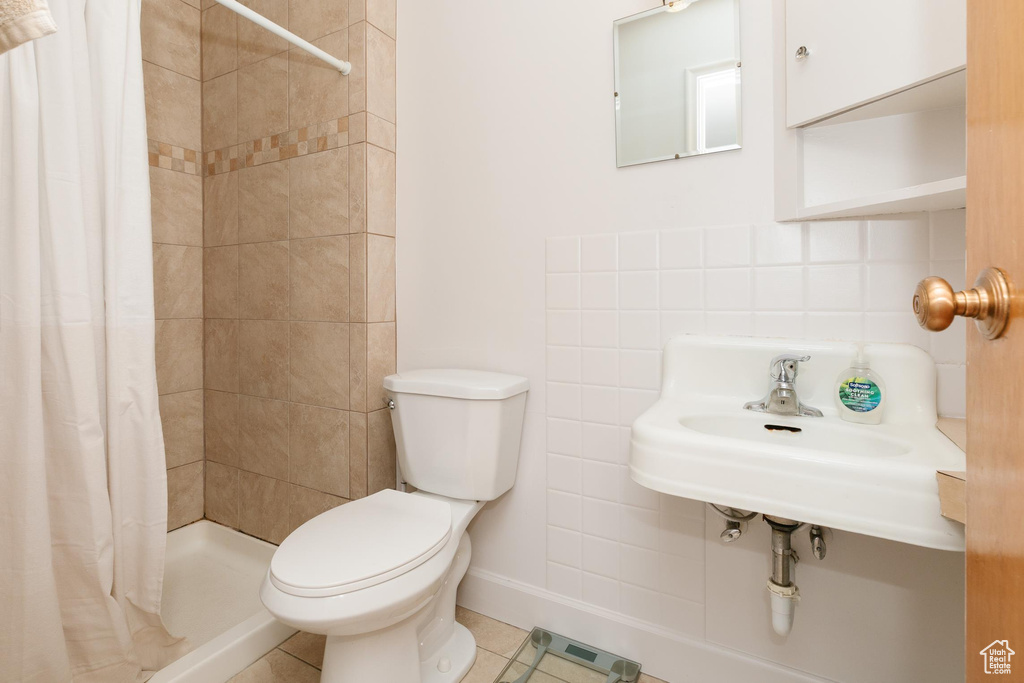 Bathroom featuring toilet, a stall shower, tile patterned floors, baseboards, and decorative backsplash