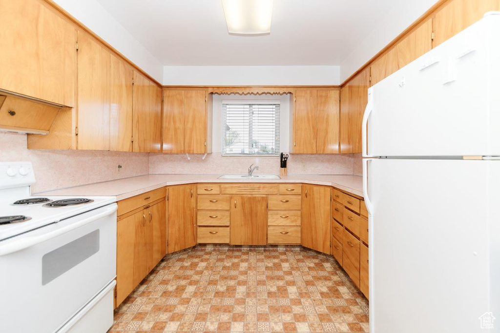 Kitchen with a sink, white appliances, light countertops, and backsplash