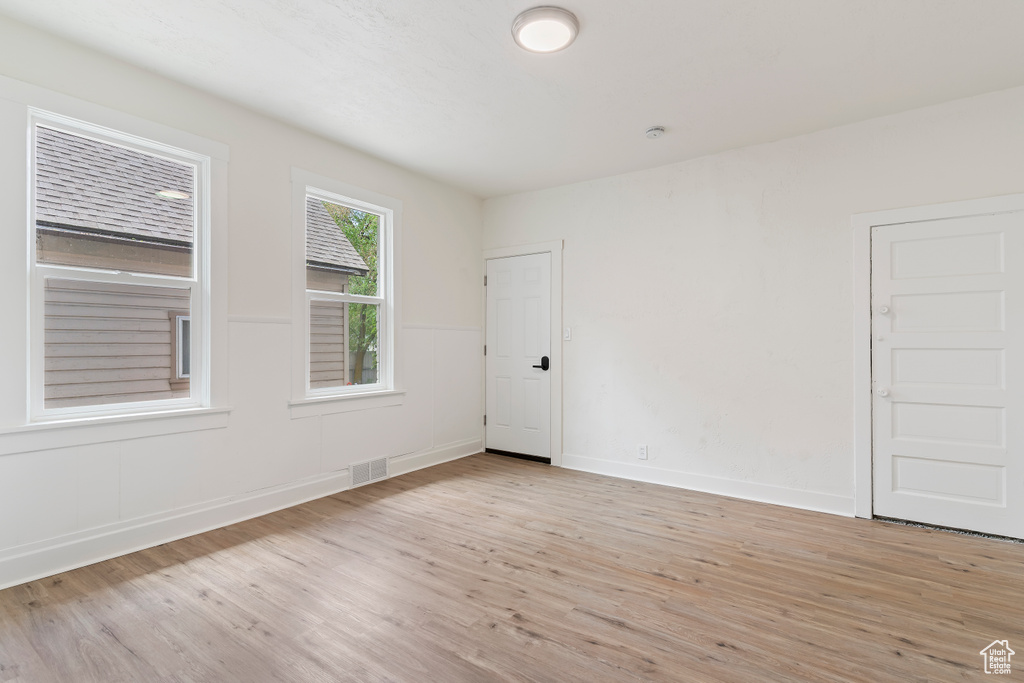 Unfurnished room featuring visible vents, light wood-style flooring, and baseboards