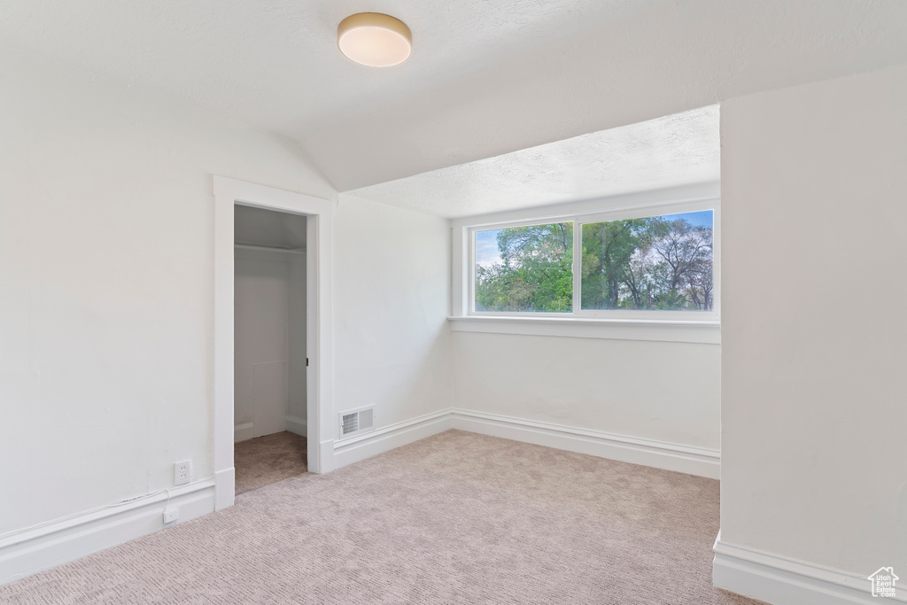 Unfurnished bedroom with carpet flooring, a closet, visible vents, baseboards, and vaulted ceiling