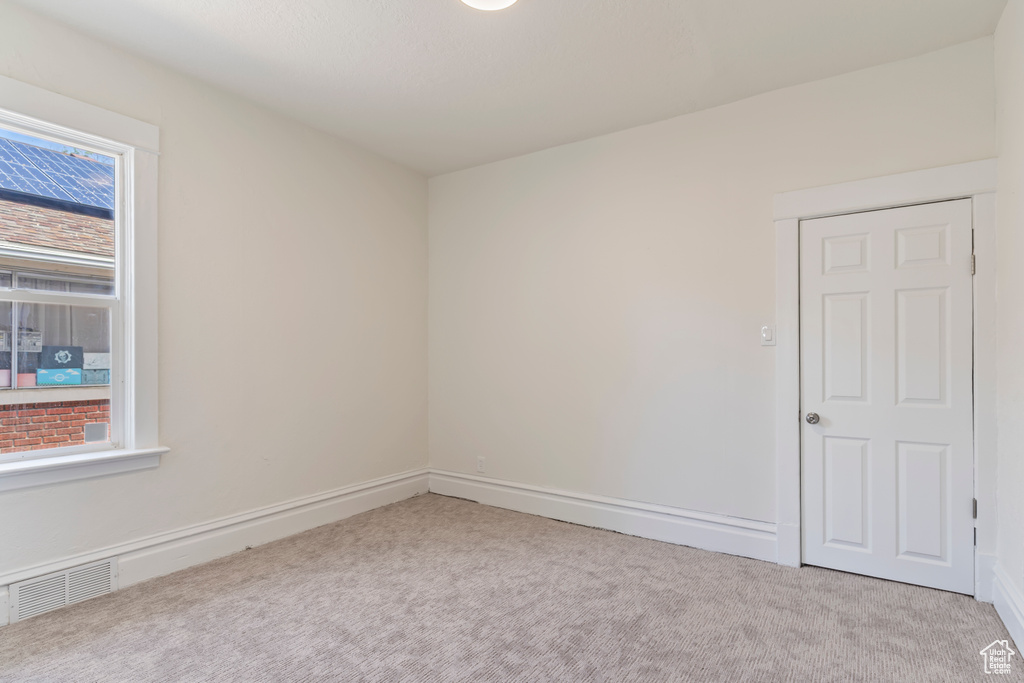 Carpeted spare room featuring baseboards and visible vents