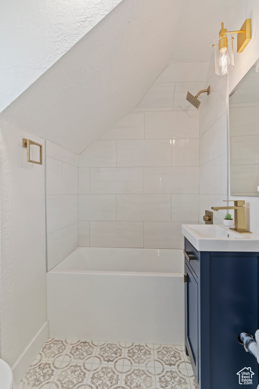 Full bathroom with  shower combination, tile patterned floors, baseboards, vaulted ceiling, and vanity