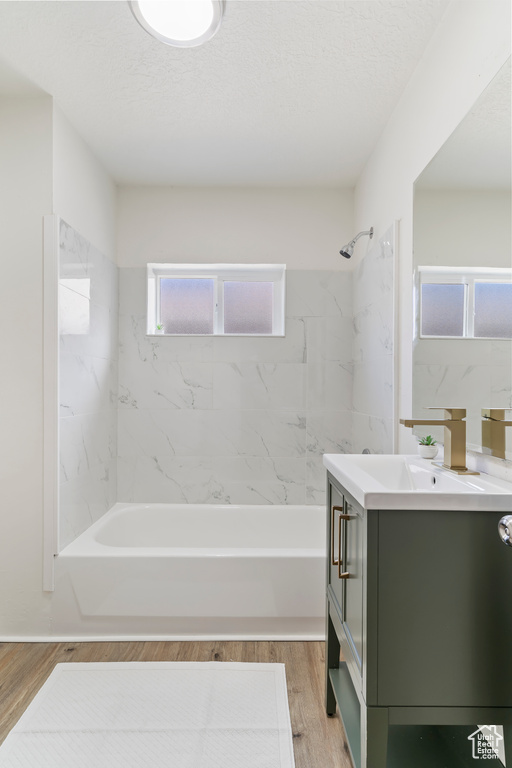 Full bath featuring bathing tub / shower combination, vanity, a textured ceiling, and wood finished floors