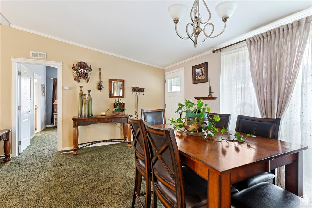 Carpeted dining room with crown molding, visible vents, baseboards, and an inviting chandelier