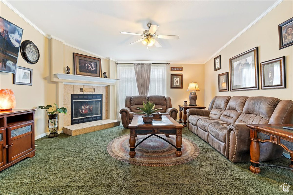 Carpeted living area with crown molding, a tile fireplace, and ceiling fan