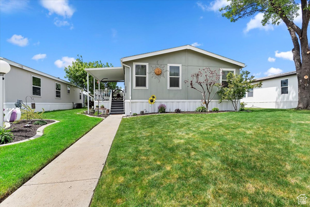 Manufactured / mobile home featuring a front lawn, a porch, and central AC unit