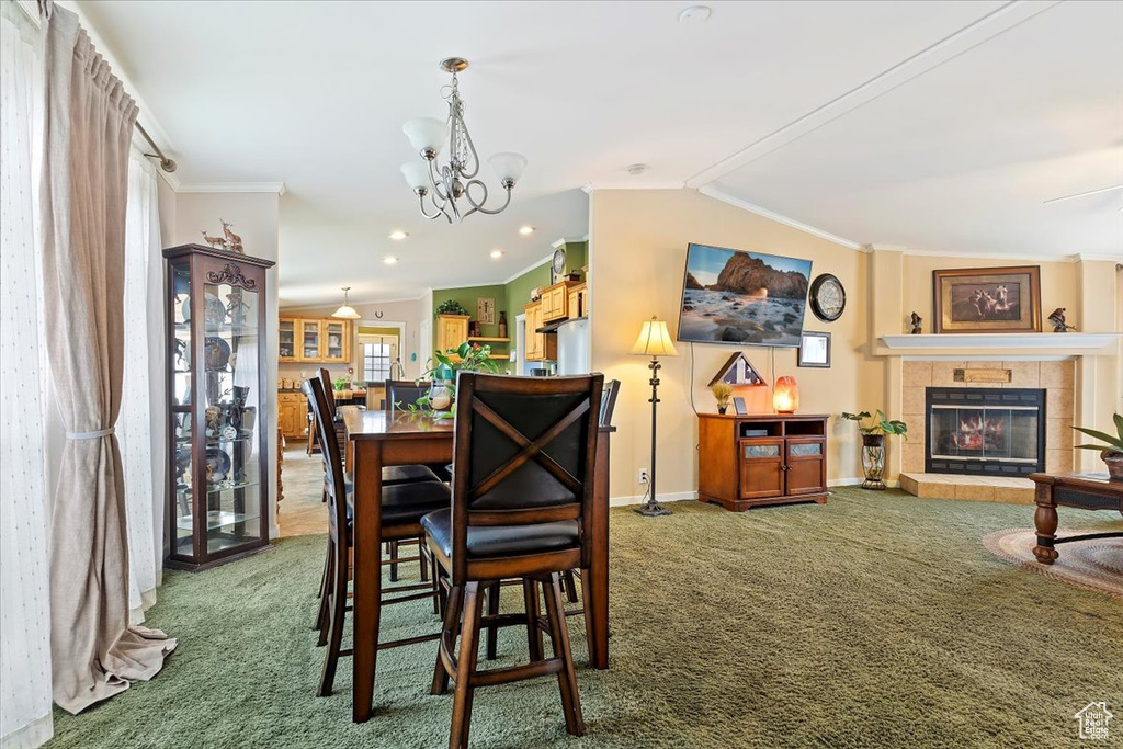 Dining room with ornamental molding, a fireplace, an inviting chandelier, carpet floors, and baseboards