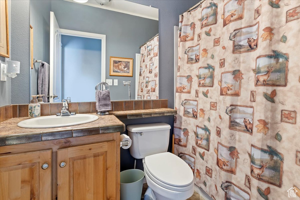Bathroom with curtained shower, vanity, and toilet