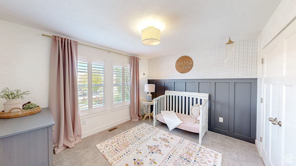 Bedroom with wallpapered walls, light carpet, and baseboards