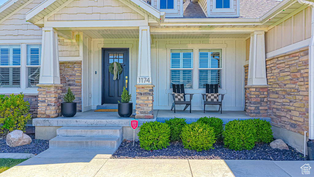 Entrance to property with a porch, board and batten siding, and stone siding