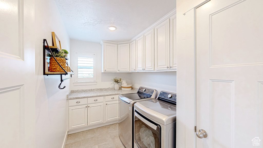 Washroom with separate washer and dryer, cabinet space, and a textured ceiling