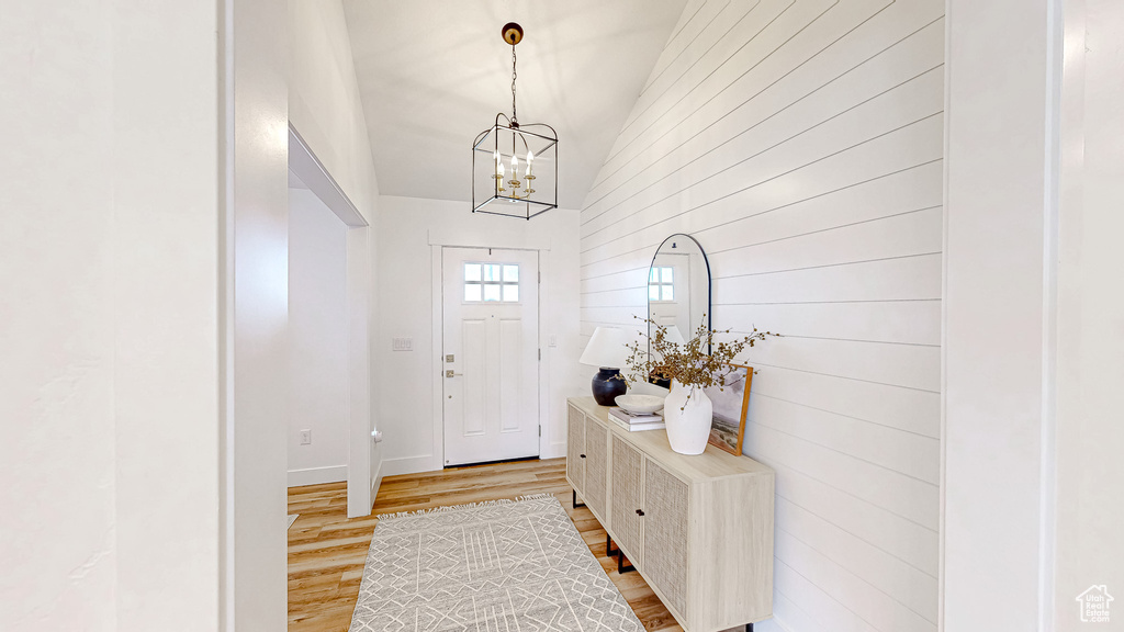 Foyer with a chandelier, light wood finished floors, lofted ceiling, and baseboards
