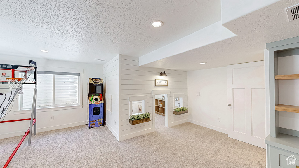 Rec room featuring a textured ceiling, carpet, baseboards, recessed lighting, and a fireplace