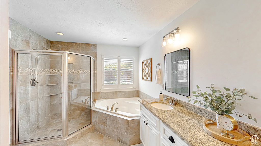 Bathroom featuring a bath, a textured ceiling, a stall shower, vanity, and tile patterned floors