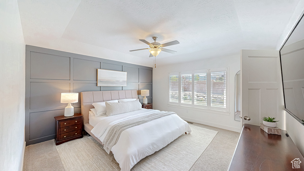 Bedroom with baseboards, light colored carpet, a decorative wall, and ceiling fan