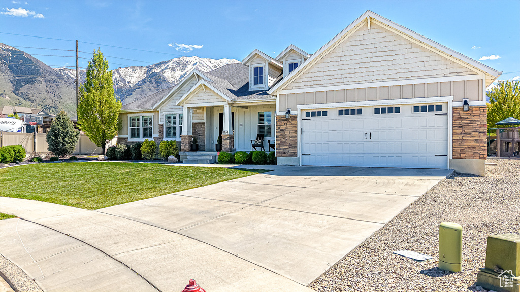 Craftsman inspired home with board and batten siding, driveway, an attached garage, a front lawn, and a mountain view