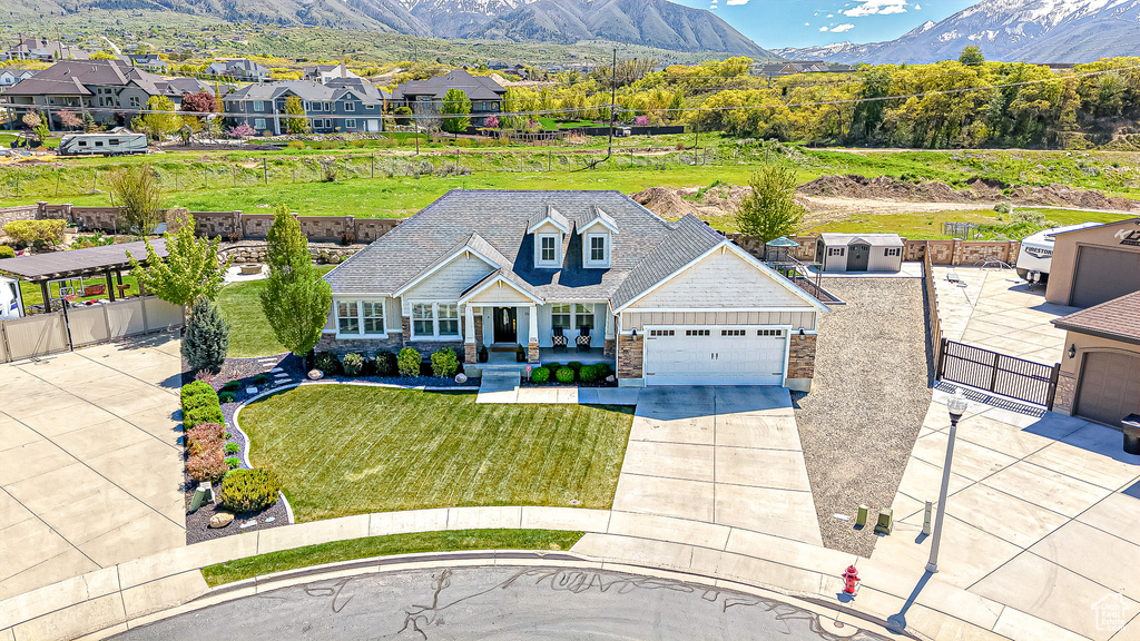 View of front of property featuring stone siding, driveway, an attached garage, and a mountain view