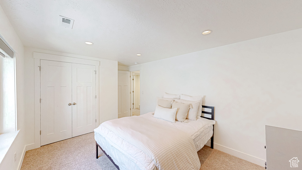 Bedroom with light colored carpet, recessed lighting, a closet, and baseboards