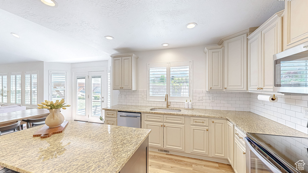 Kitchen featuring a sink, appliances with stainless steel finishes, light wood finished floors, recessed lighting, and backsplash