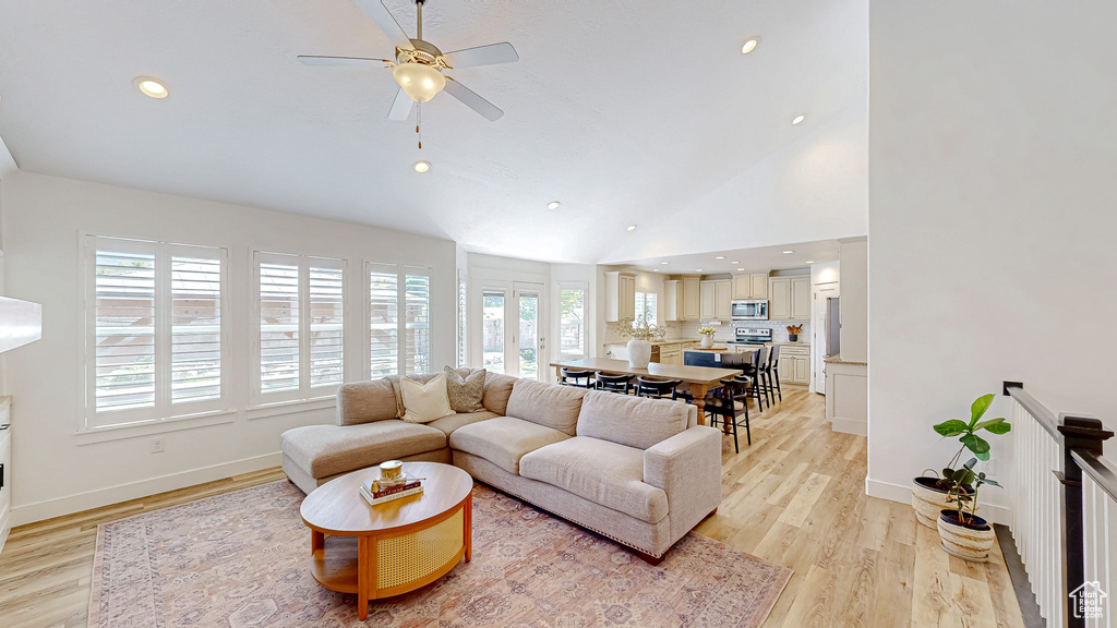 Living room with healthy amount of natural light, ceiling fan, light wood-style flooring, vaulted ceiling, and recessed lighting