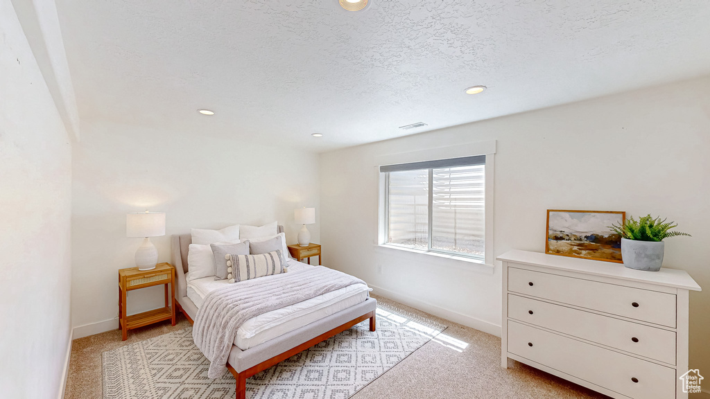 Bedroom featuring baseboards, recessed lighting, light colored carpet, and a textured ceiling