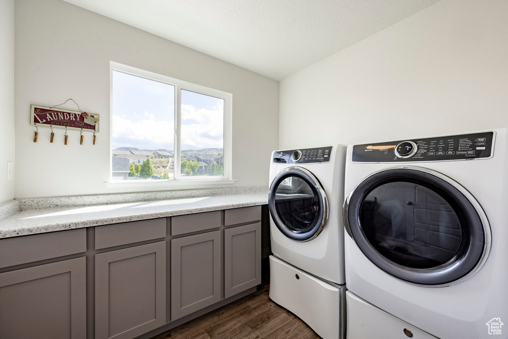 Laundry room with washing machine and clothes dryer, dark wood finished floors, and cabinet space