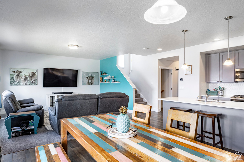 Dining space with dark wood-style floors, stairway, a textured ceiling, and recessed lighting