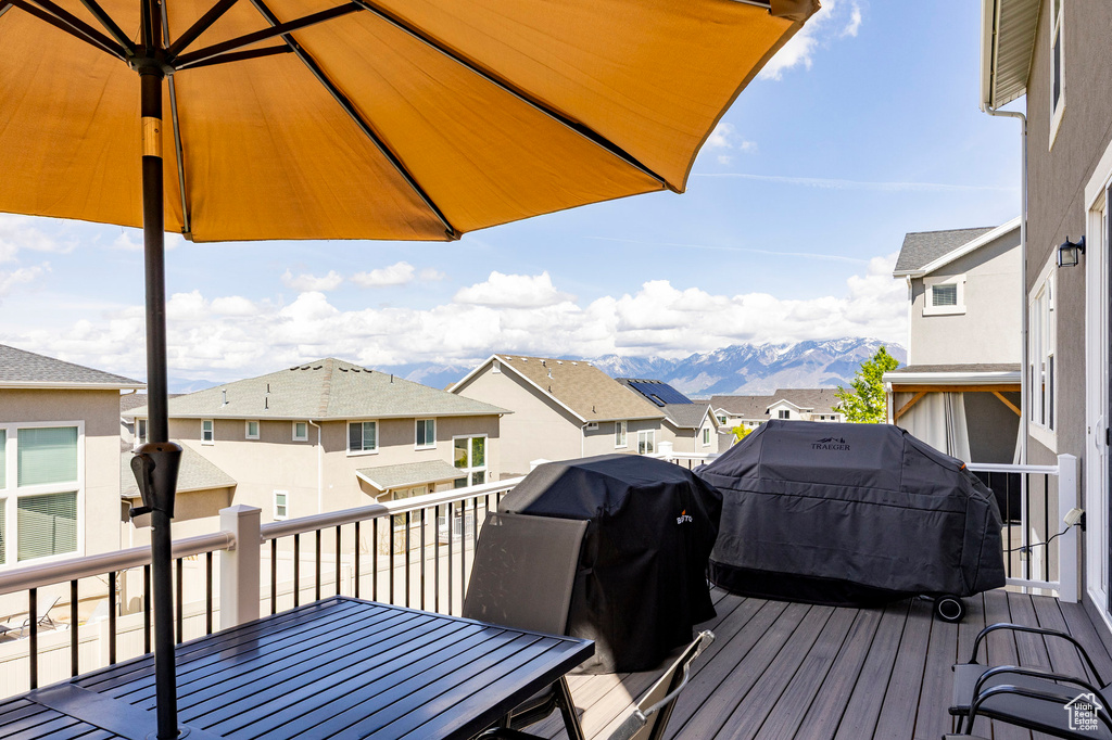 Wooden terrace with a residential view, outdoor dining area, and area for grilling