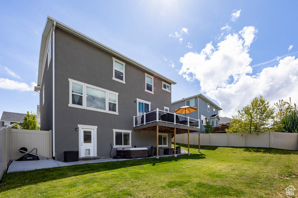 Rear view of house featuring a hot tub, a deck, stucco siding, and a patio area