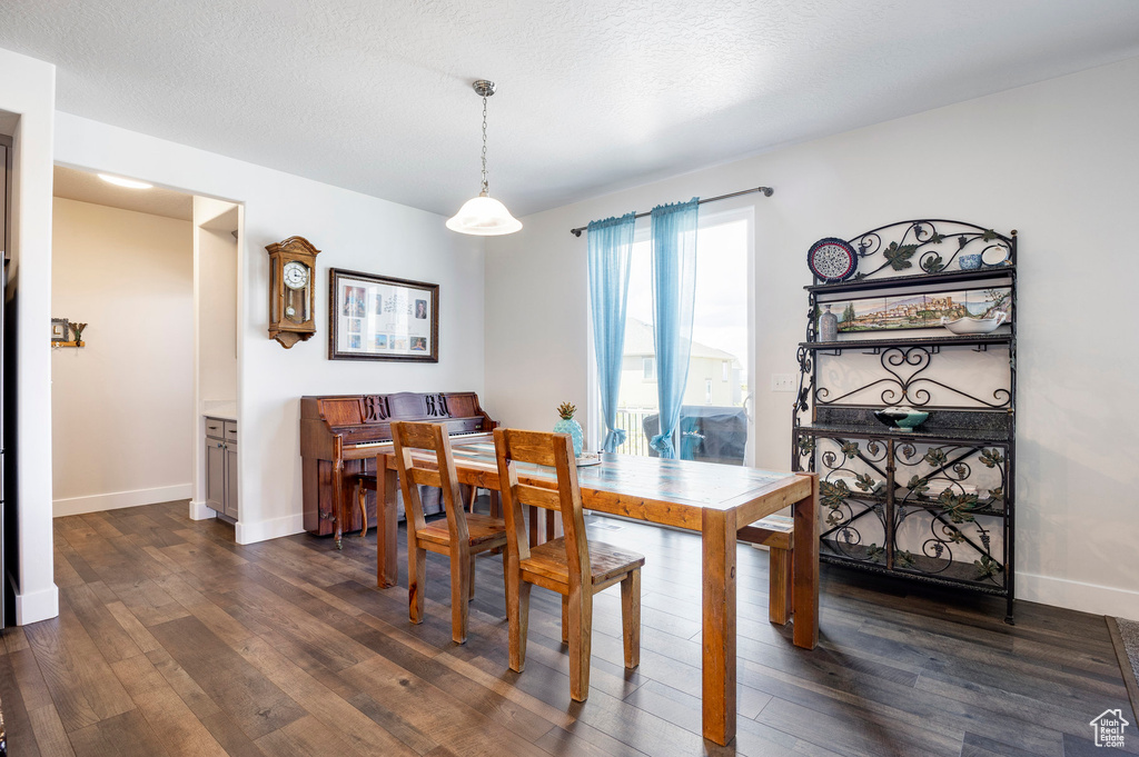 Dining room featuring dark wood-style flooring and baseboards