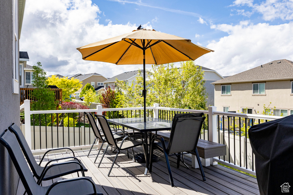 Wooden deck with outdoor dining area, a residential view, and a grill