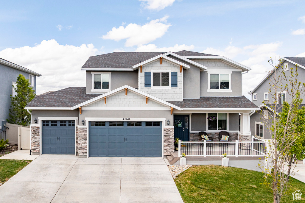Craftsman-style house featuring covered porch, concrete driveway, an attached garage, stone siding, and roof with shingles