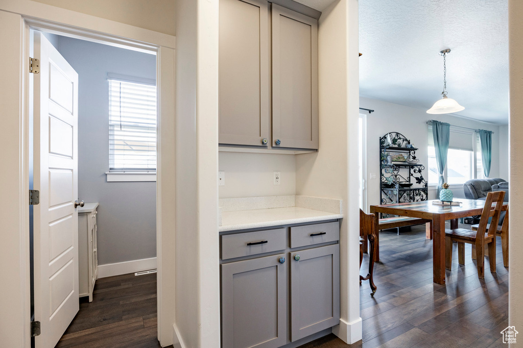 Kitchen with gray cabinets, dark wood finished floors, light countertops, pendant lighting, and baseboards