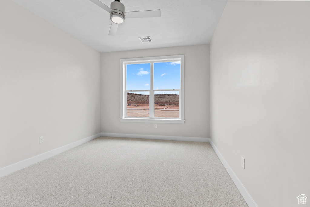 Unfurnished room featuring light colored carpet, baseboards, and a ceiling fan