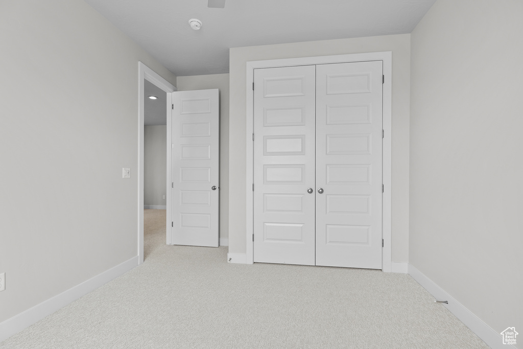 Unfurnished bedroom with carpet, a closet, and baseboards