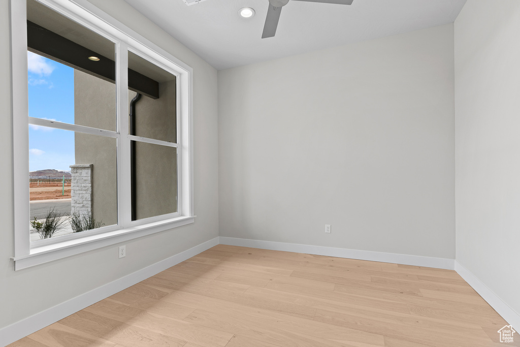 Spare room with wood finished floors, a ceiling fan, baseboards, and recessed lighting
