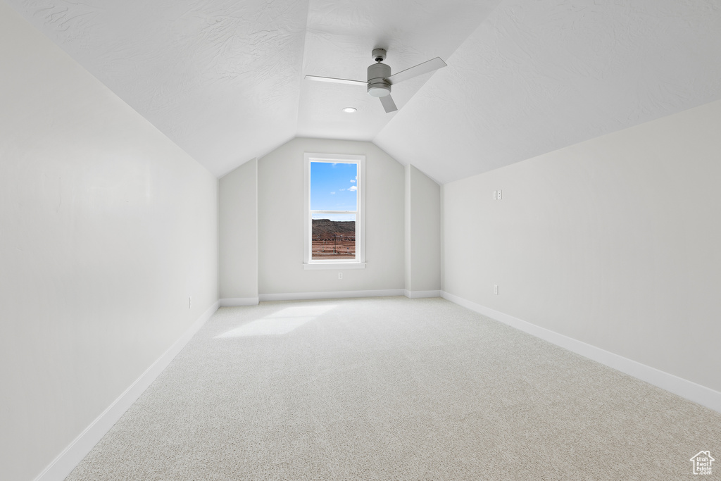 Bonus room with lofted ceiling, carpet flooring, baseboards, and a ceiling fan