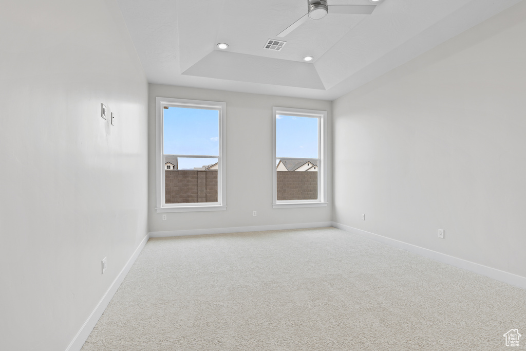 Empty room with a ceiling fan, baseboards, and light colored carpet