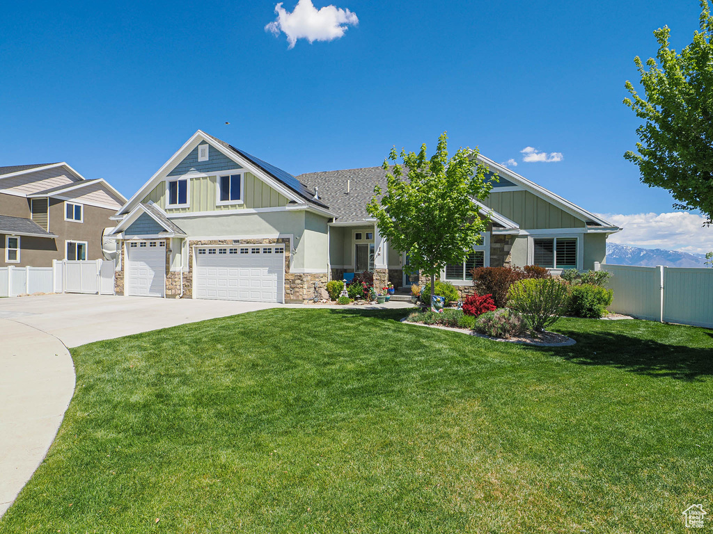 Craftsman house featuring stone siding, board and batten siding, roof mounted solar panels, concrete driveway, and a garage