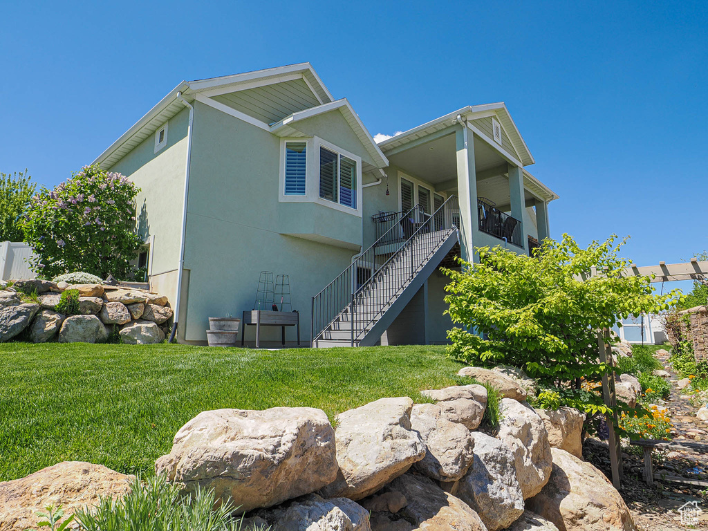 View of property exterior featuring stairway, a yard, and stucco siding